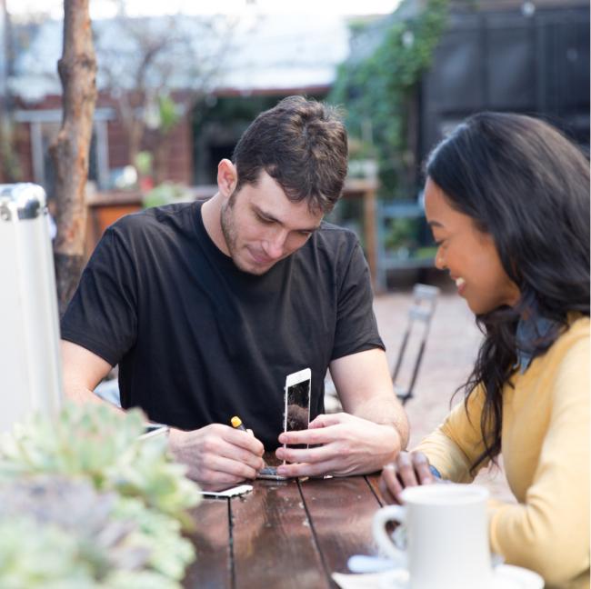 man repairing woman's phone on patio